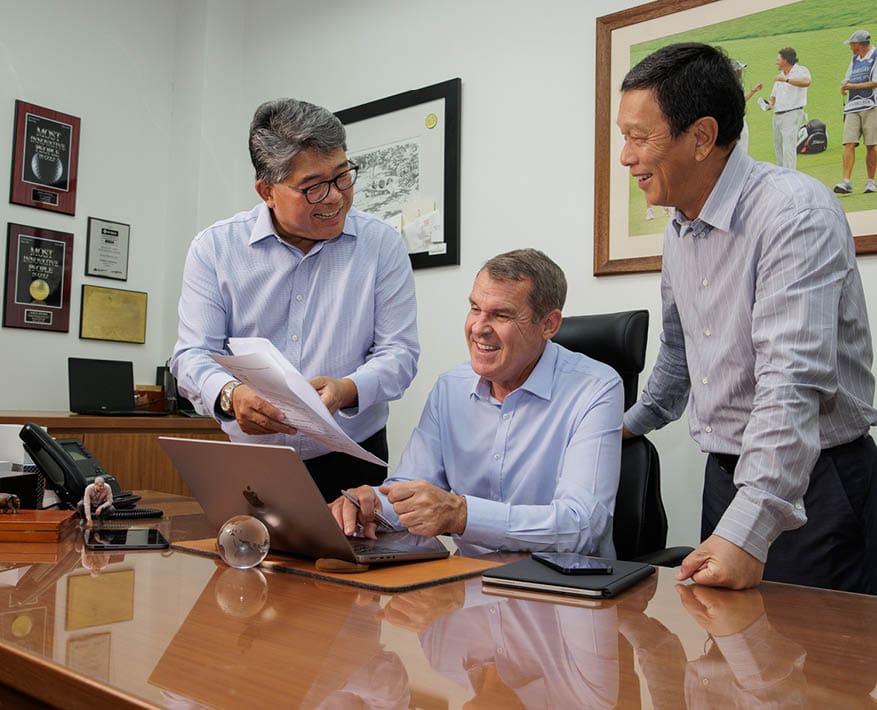 Three men are in a room, two of them are smiling and one is using a laptop. AI generated content