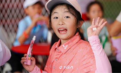 A young girl wearing a pink jacket is holding a toothbrush and smiling. AI generated content