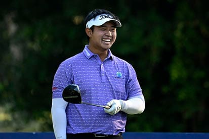 A man wearing a purple polo shirt and a white visor is holding a golf club. AI generated content