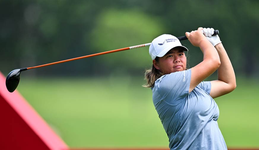 A woman in a blue shirt is swinging a golf club at a ball. AI generated content